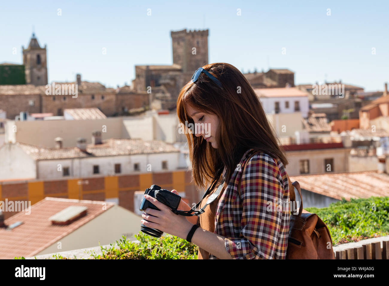 Une jeune touriste rousse avec un sac à dos prend des photos de la vieille ville de Caceres du point de vue de Galarza Banque D'Images