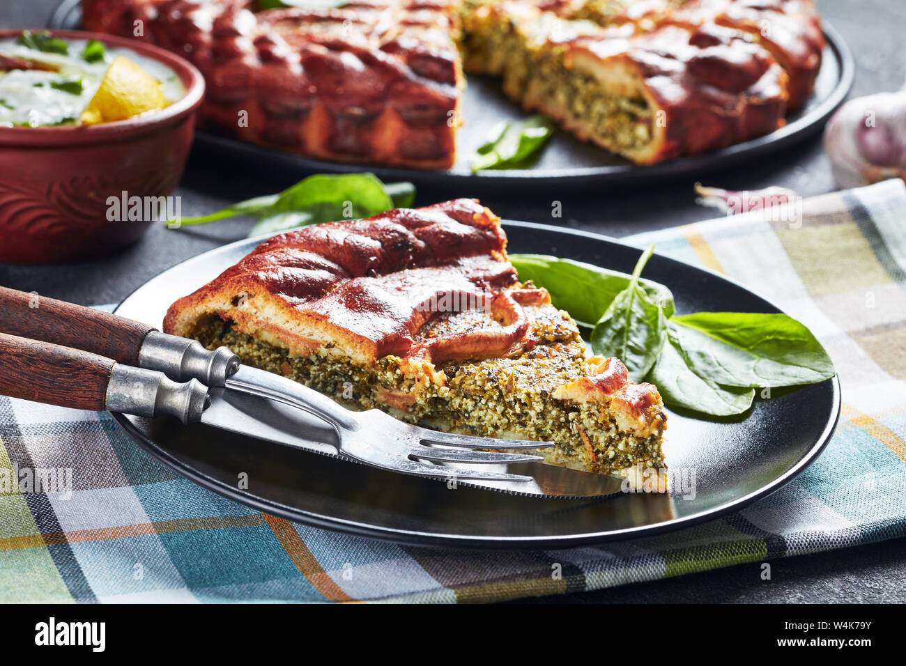 Close-up d'une tranche de tarte Ricotta Épinards servi sur une plaque noire avec des tranches de gâteau à l'arrière-plan, vue horizontale d'en haut Banque D'Images