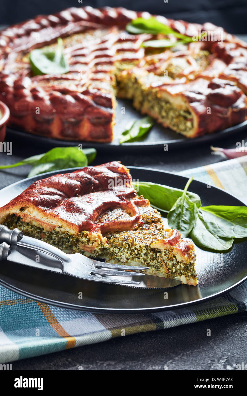 Close-up d'une tranche de tarte Ricotta Épinards servi sur une plaque noire avec des tranches de gâteau à l'arrière-plan, vue verticale d'en haut Banque D'Images