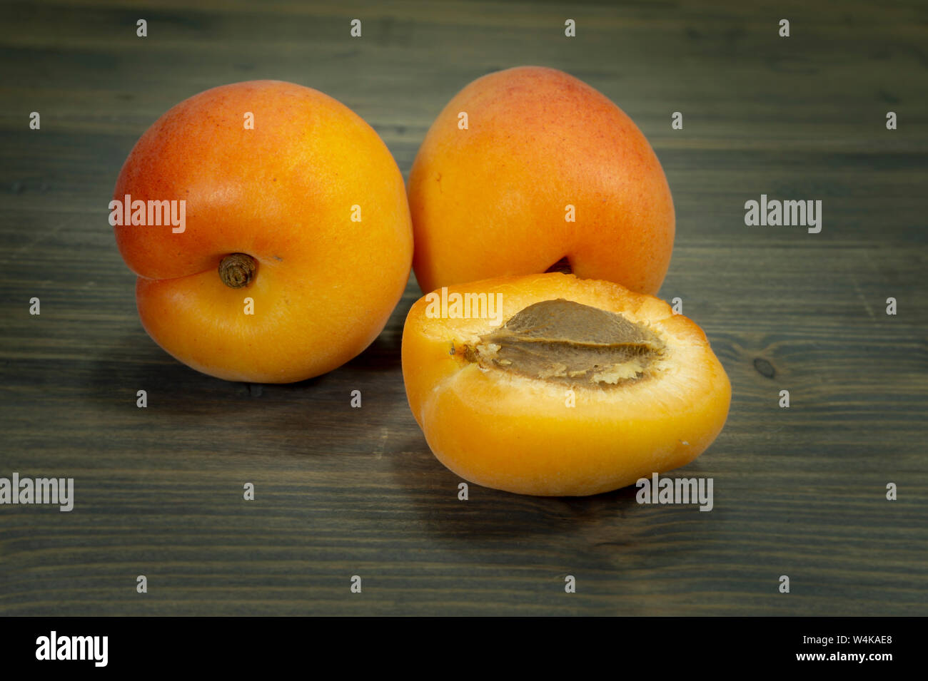 Poisson frais entier et tranchées abricots coupés en deux sur une table en bois rustique dans une vue en gros plan Banque D'Images
