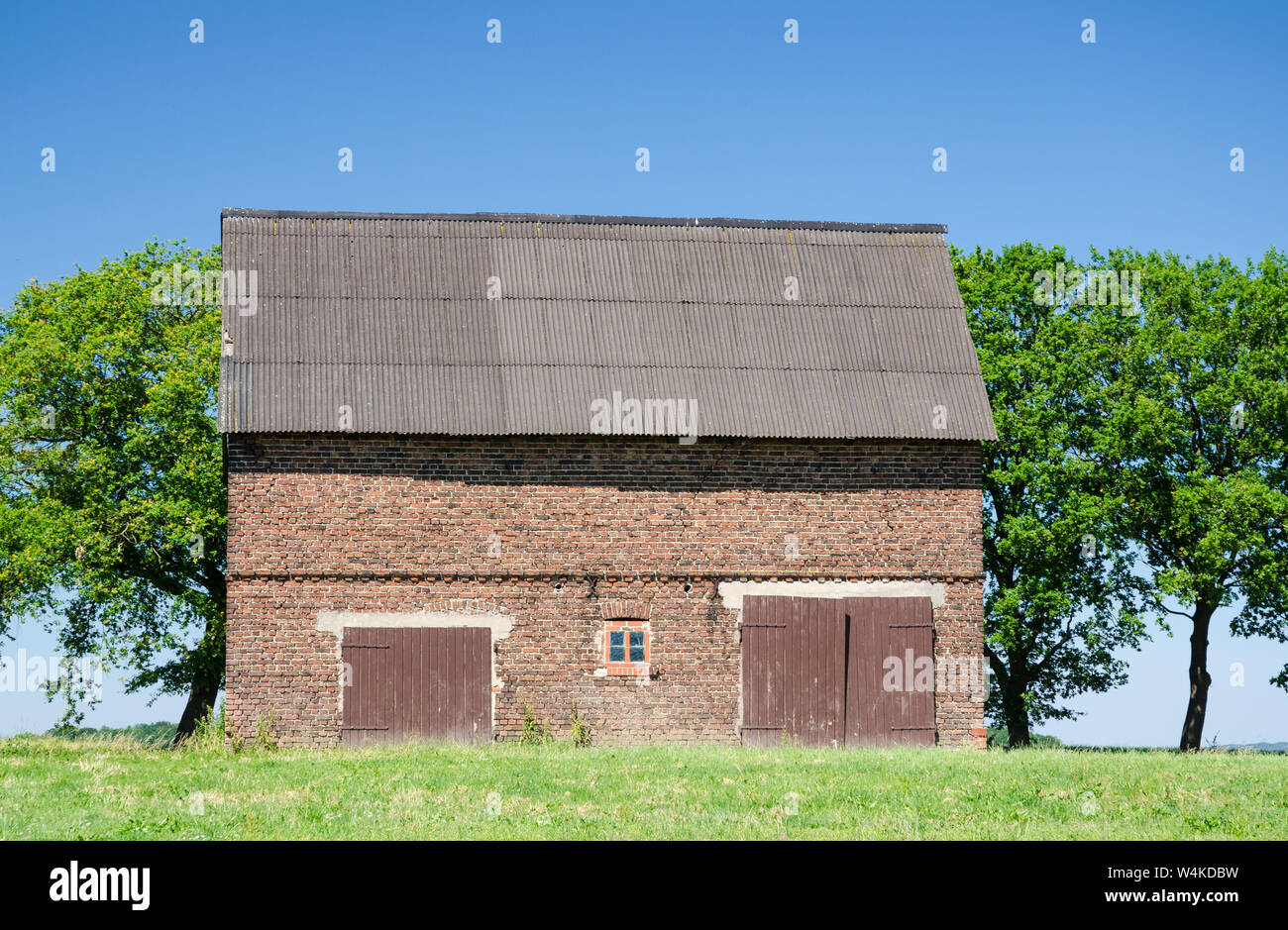 Grange abandonnée faite de briques rouges avec des portes en bois en Bavière, Allemagne Banque D'Images