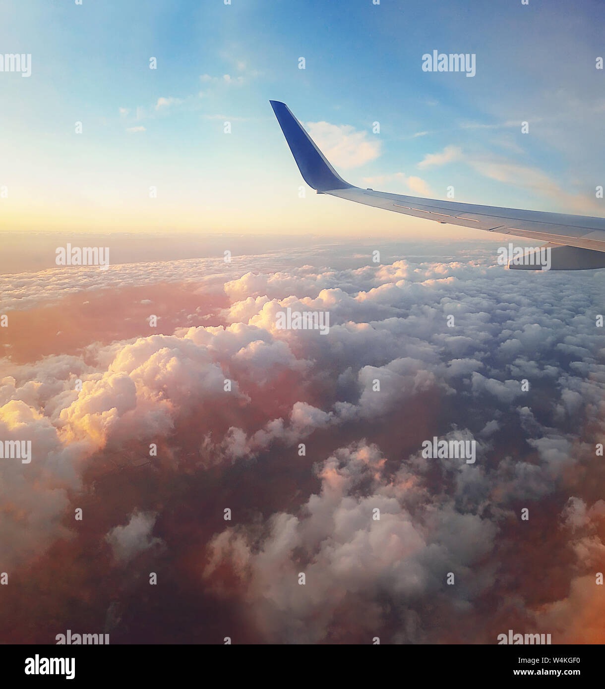 Scène aérienne d'un avion vol au-dessus de la coucher du soleil nuages duveteux de couleur. Aile d'avion vu à travers la fenêtre. Voler vers le ciel au-dessus de l'horizon. Tra Banque D'Images