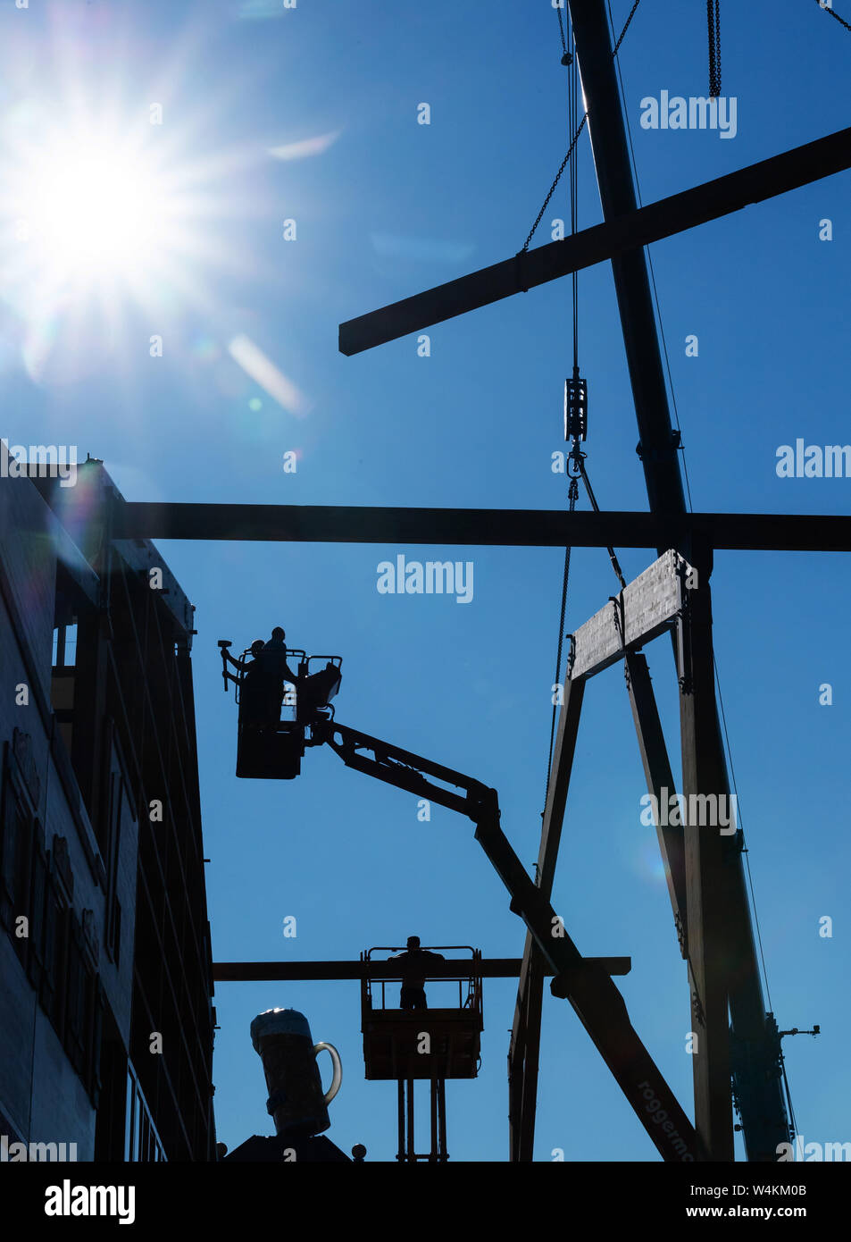 Munich, Allemagne. 24 juillet, 2019. Dans la lumière du soleil sous un ciel bleu acier le matin, les travailleurs doivent utiliser une grue pour assembler la structure du toit en poutres d'une tente à bière sur le site de l'Oktoberfest. L'Oktoberfest se déroule cette année du 21 septembre au 6 octobre. L'Allemagne est confrontée à une vague de chaleur - et déjà le Mercredi ce sera clairement visible dans de nombreux domaines. Crédit : Peter Kneffel/dpa/Alamy Live News Banque D'Images