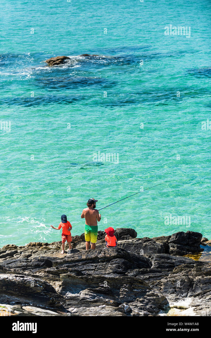 Un père pêchant avec ses deux jeunes enfants en vacances de marche sur les rochers de Fistral à Newquay en Cornouailles. Banque D'Images