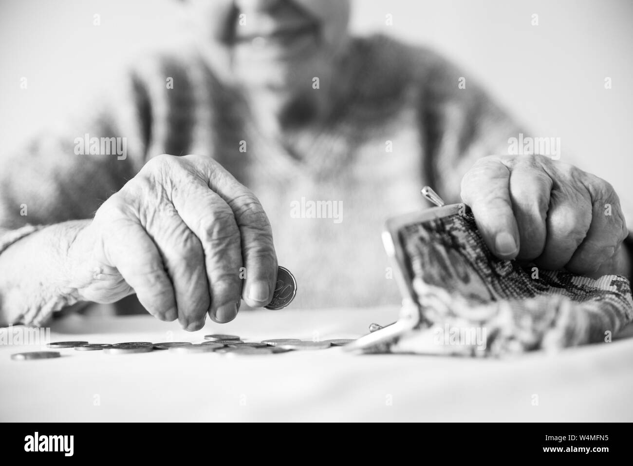 Photo gros plan détaillé de womans mains âgées méconnaissable restants de comptage de pièces dans son portefeuille de retraite après le paiement des factures. Le noir et blanc Banque D'Images