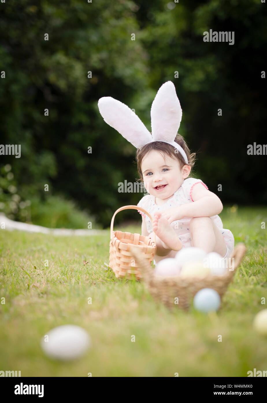1 ans tout-petit en costume de lapin de Pâques ramasser des œufs à l'extérieur Banque D'Images