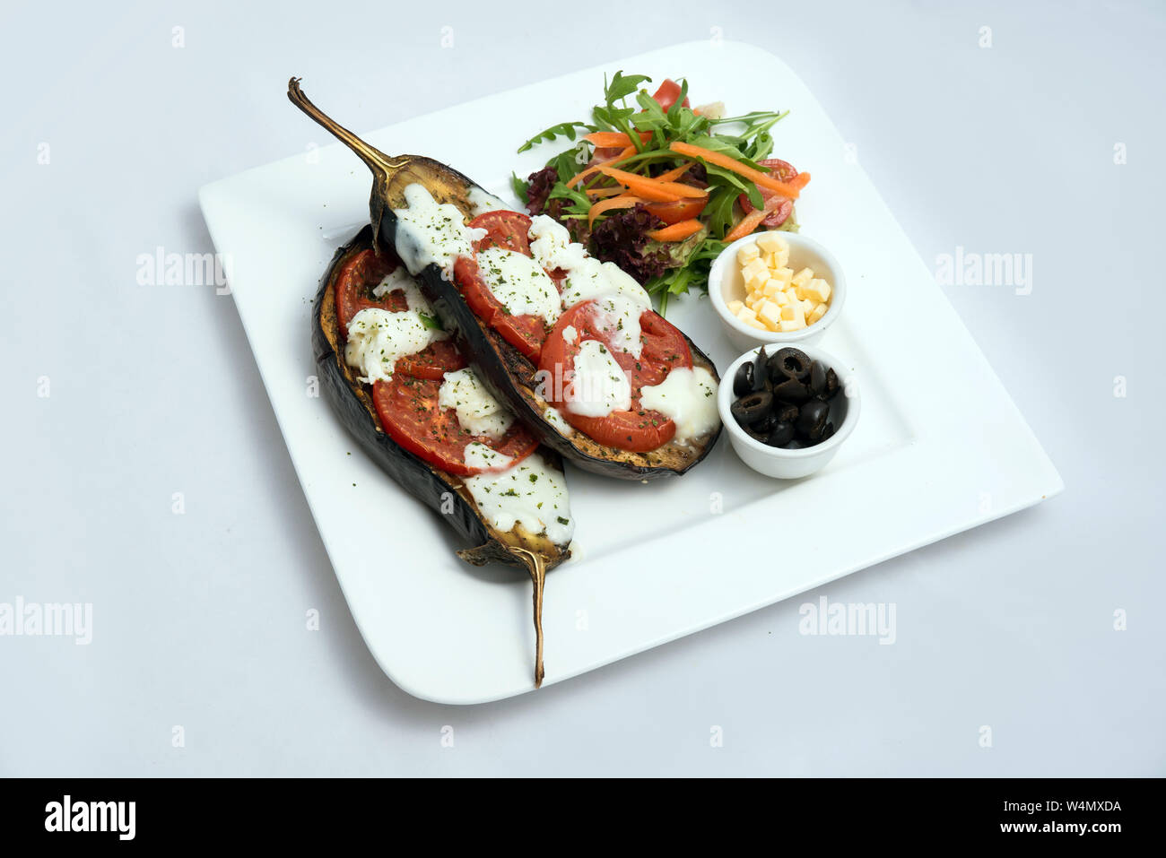 Un héros chaud à faible contraste d'un plat principal plat avec de l'aubergine grillée avec buffalo fromage, tomate, olives et légumes sur le côté, sur un minim Banque D'Images
