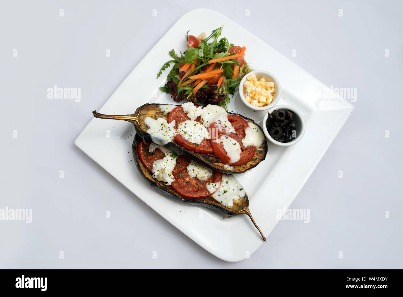 Un héros chaud à faible contraste d'un plat principal plat avec de l'aubergine grillée avec buffalo fromage, tomate, olives et légumes sur le côté, sur un minim Banque D'Images