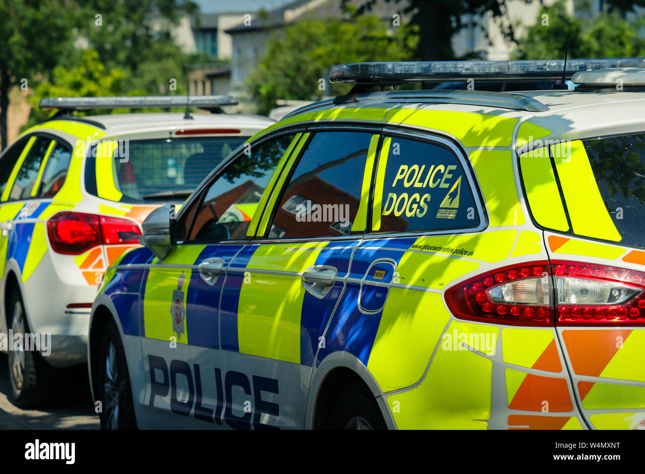 Deux voitures de police en stationnement, une unité d'un chien voiture stationnée dans l'ombre pommelé sur une chaude journée d'été Banque D'Images