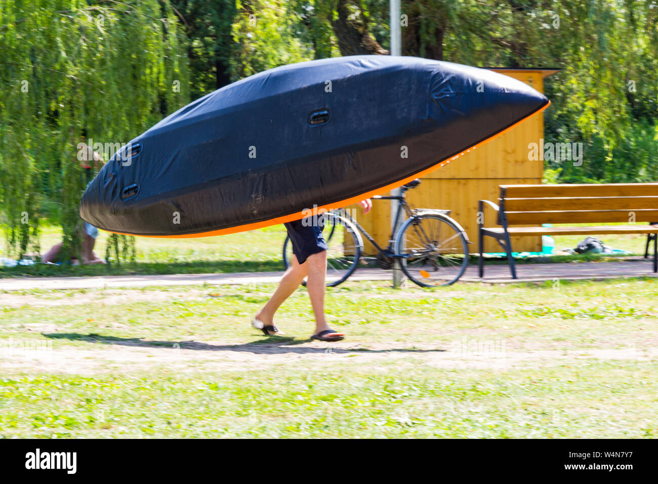 Bateau gonflable homme portant sur son épaule cache le haut du corps à la plage du lac Balaton, Hongrie Banque D'Images