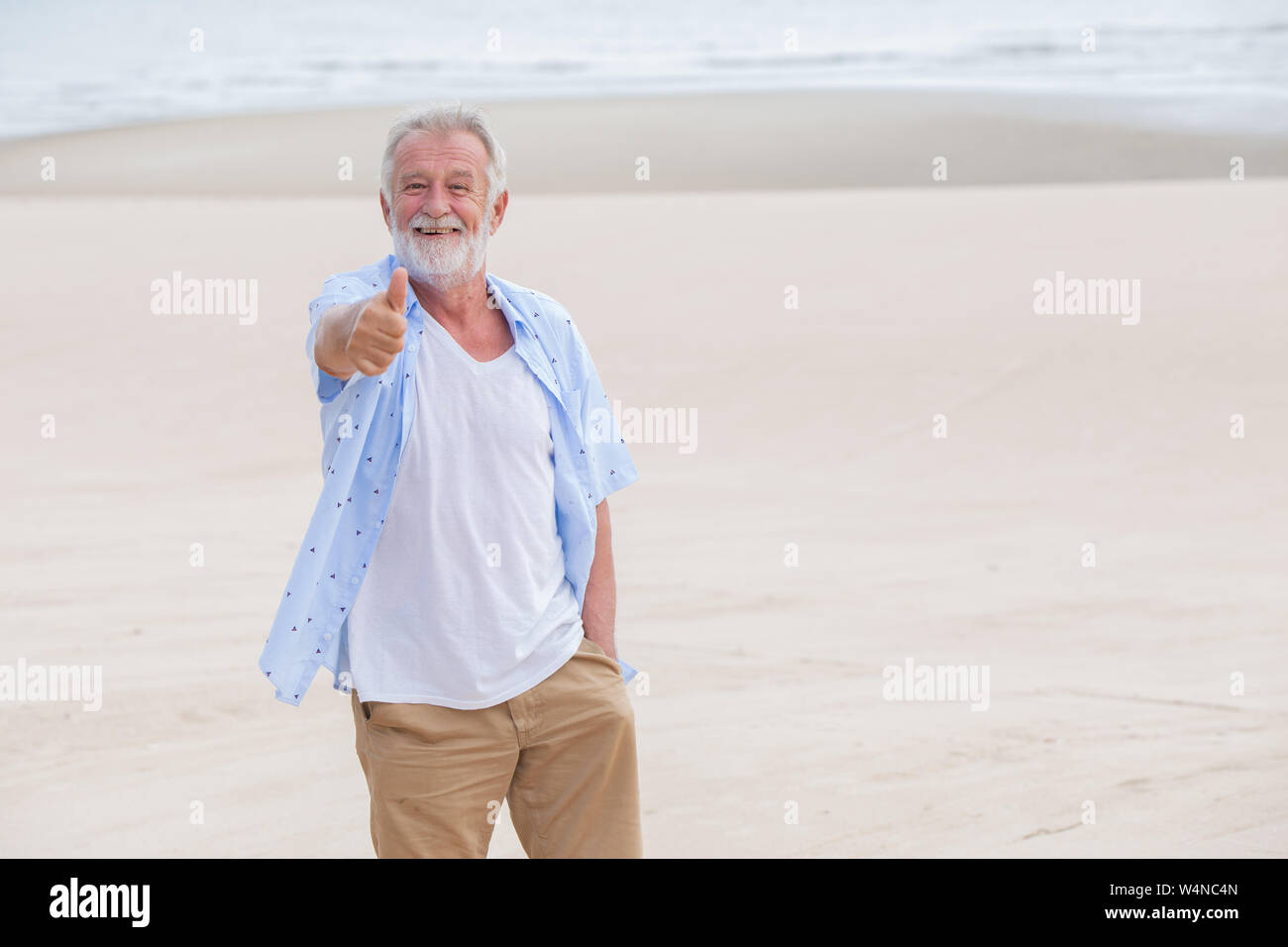 Thumbs up heureux ancien, bonne retraite seul vieil homme au fond de plage mer Banque D'Images
