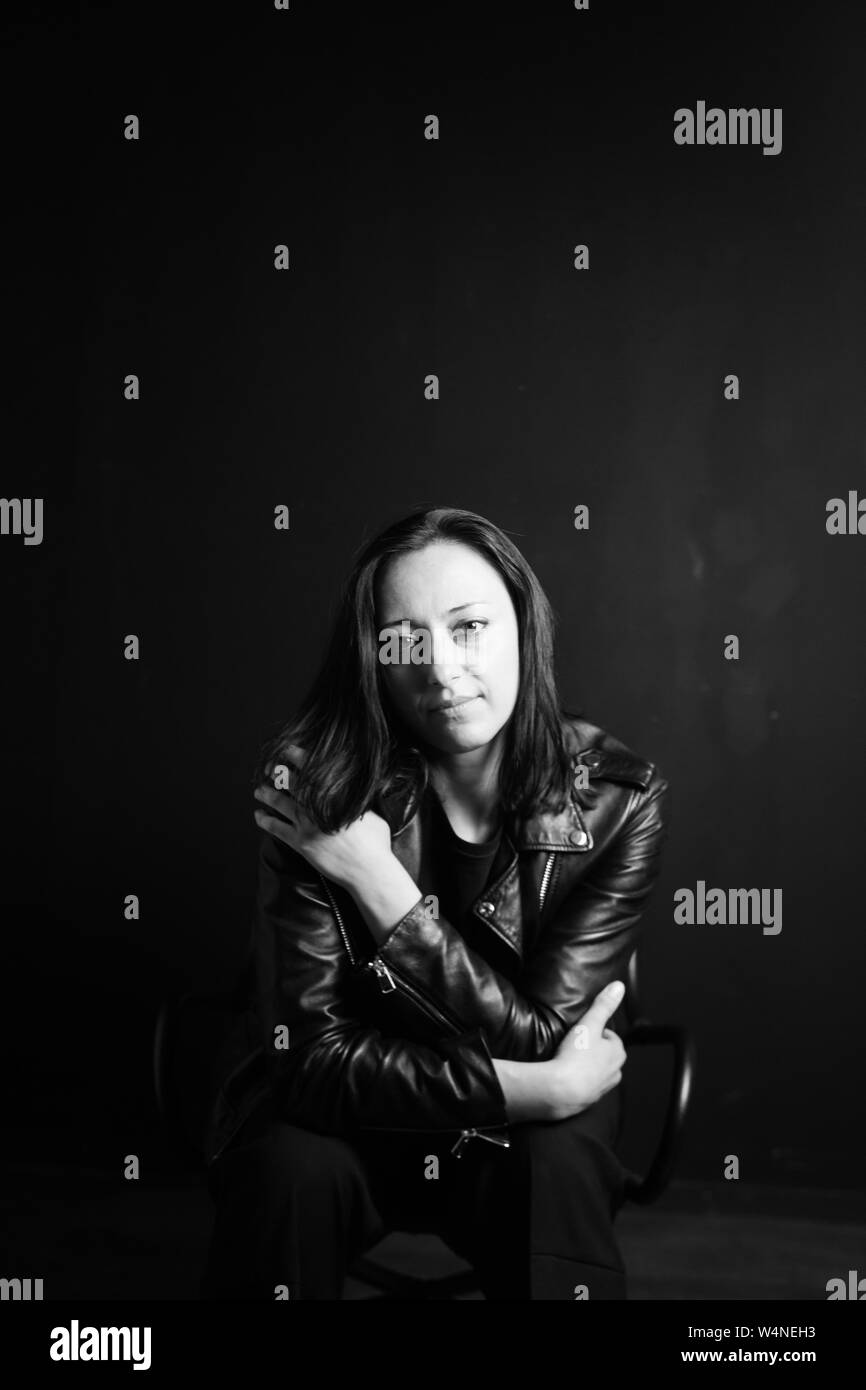 Studio portrait d'une belle jeune femme dans une veste en cuir noire contre un fond uni Banque D'Images