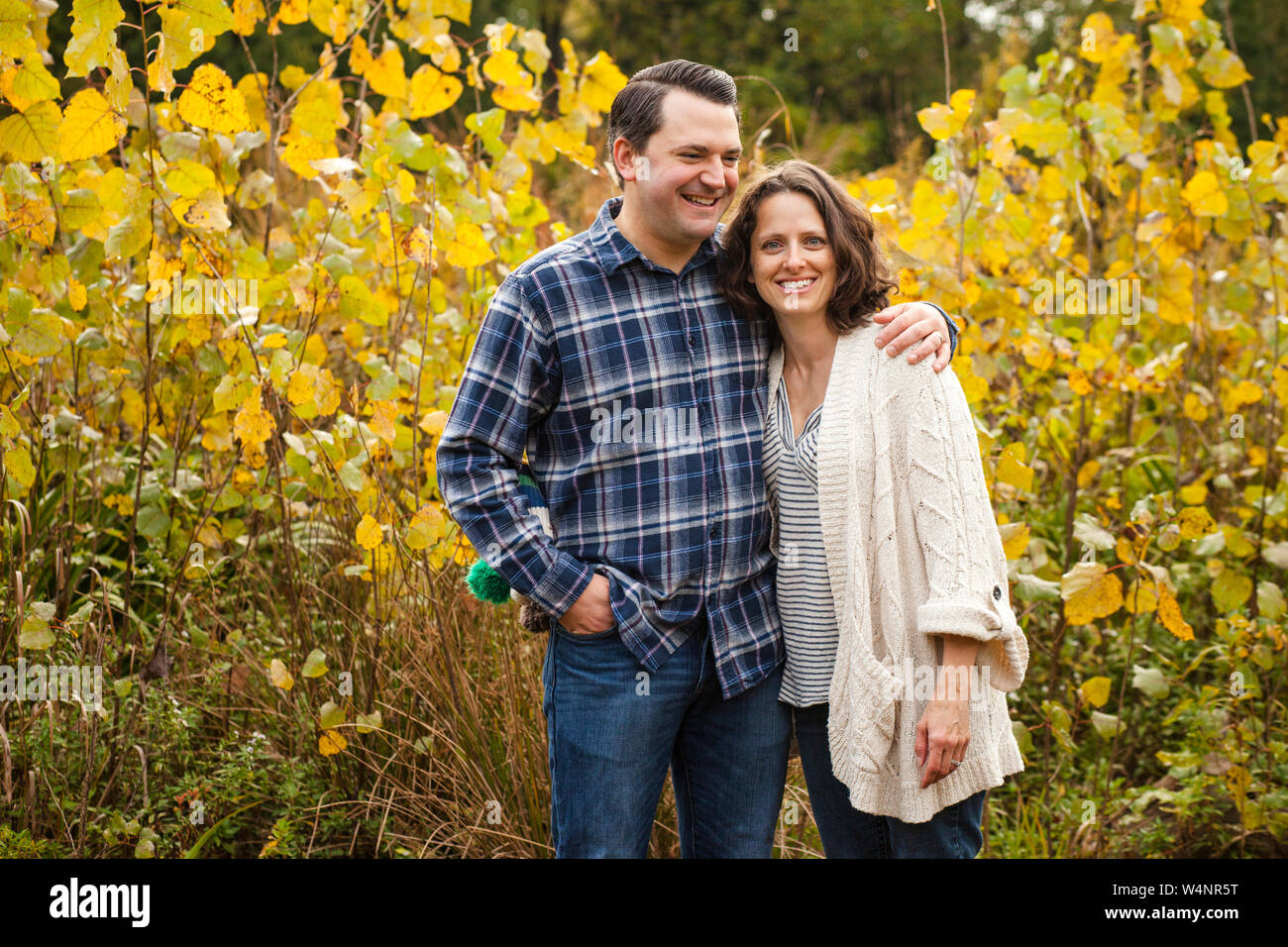 Un sourire heureux couple stand bras dessus, bras dessous dans une prairie d'or Banque D'Images