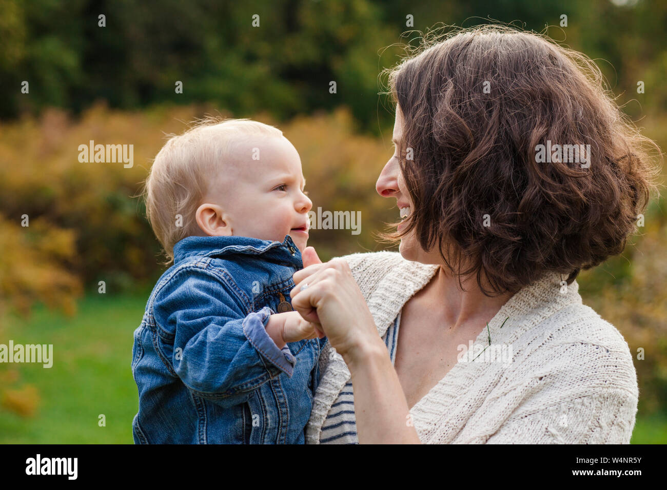 Un happy smiling mother tient son bébé dans les bras à l'extérieur Banque D'Images