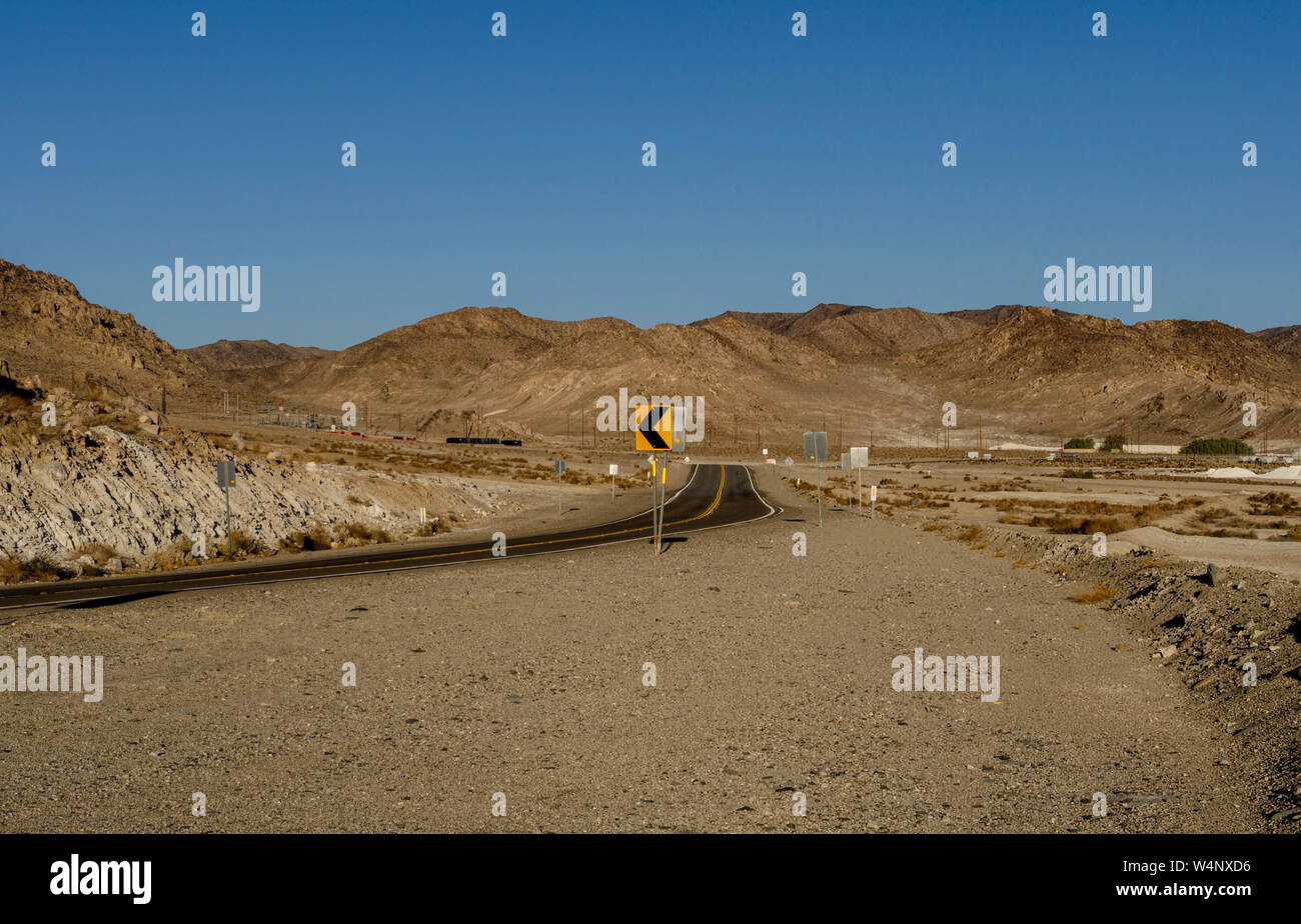 Route du désert en courbe droit chemin menant vers désert aride montagne sous un ciel bleu clair. à l'ombre, les vue de l'autoroute. Banque D'Images