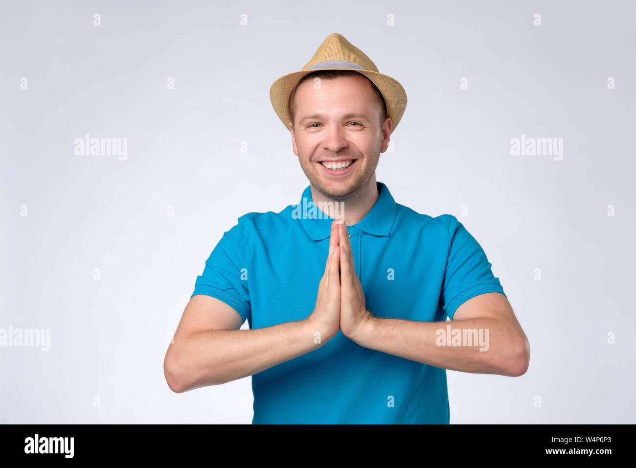 L'homme en chemise bleue holding hands in Namaste accueille ses hôtes Banque D'Images