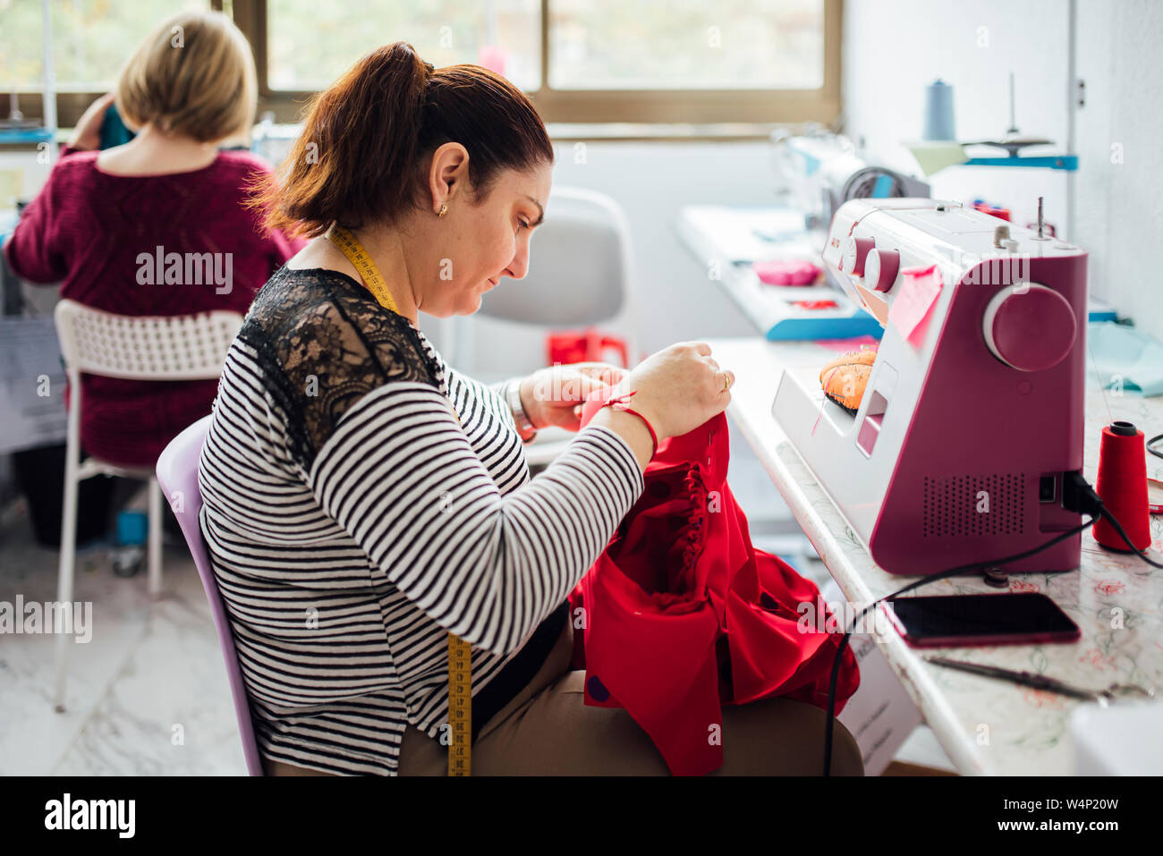 Femme adulte à l'aide d'une machine à coudre dans un atelier de couture Banque D'Images