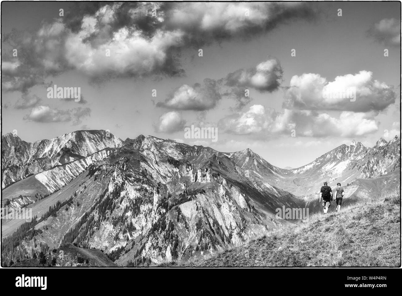 Tourné en noir et blanc d'un homme avec sac à dos et un garçon de l'arrière de la randonnée dans un paysage de montagne Banque D'Images