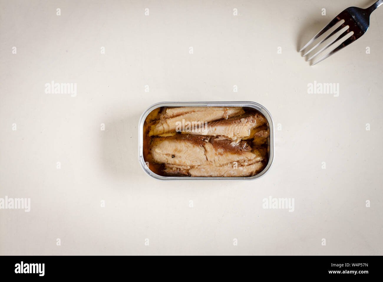 Les sardines en boîte et de la fourche sur la table rustique blanc fond Banque D'Images