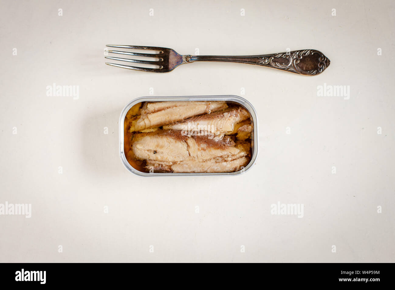 Les sardines en boîte et de la fourche sur la table rustique blanc fond Banque D'Images