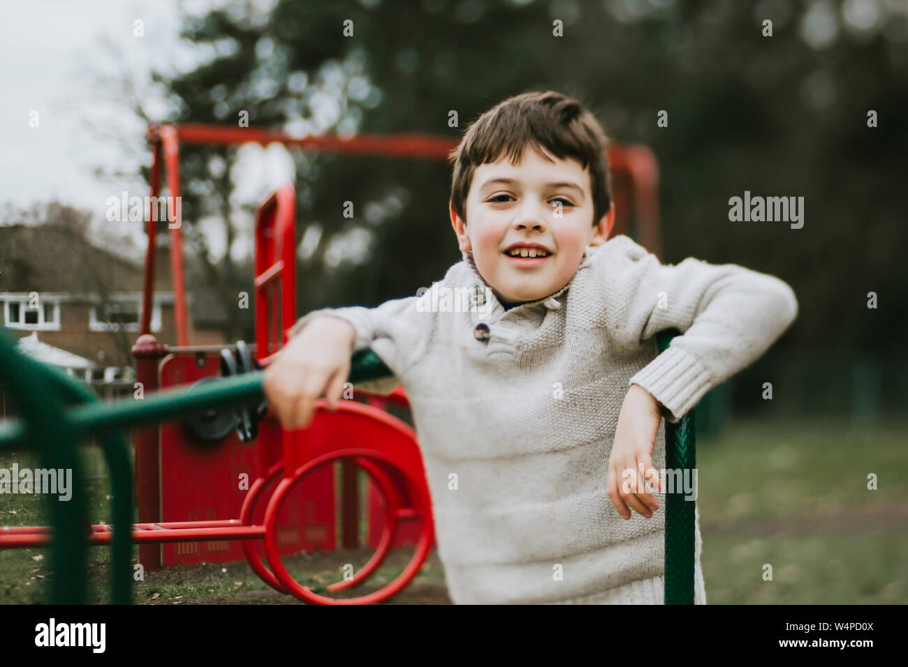 Portrait of smiling boy on merry go round à l'aire de jeux Banque D'Images