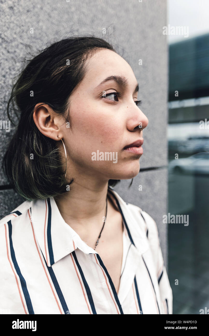 Jeune femme triste comme un travailleur s'appuyant sur le mur. Vue extérieure de la ville. Banque D'Images