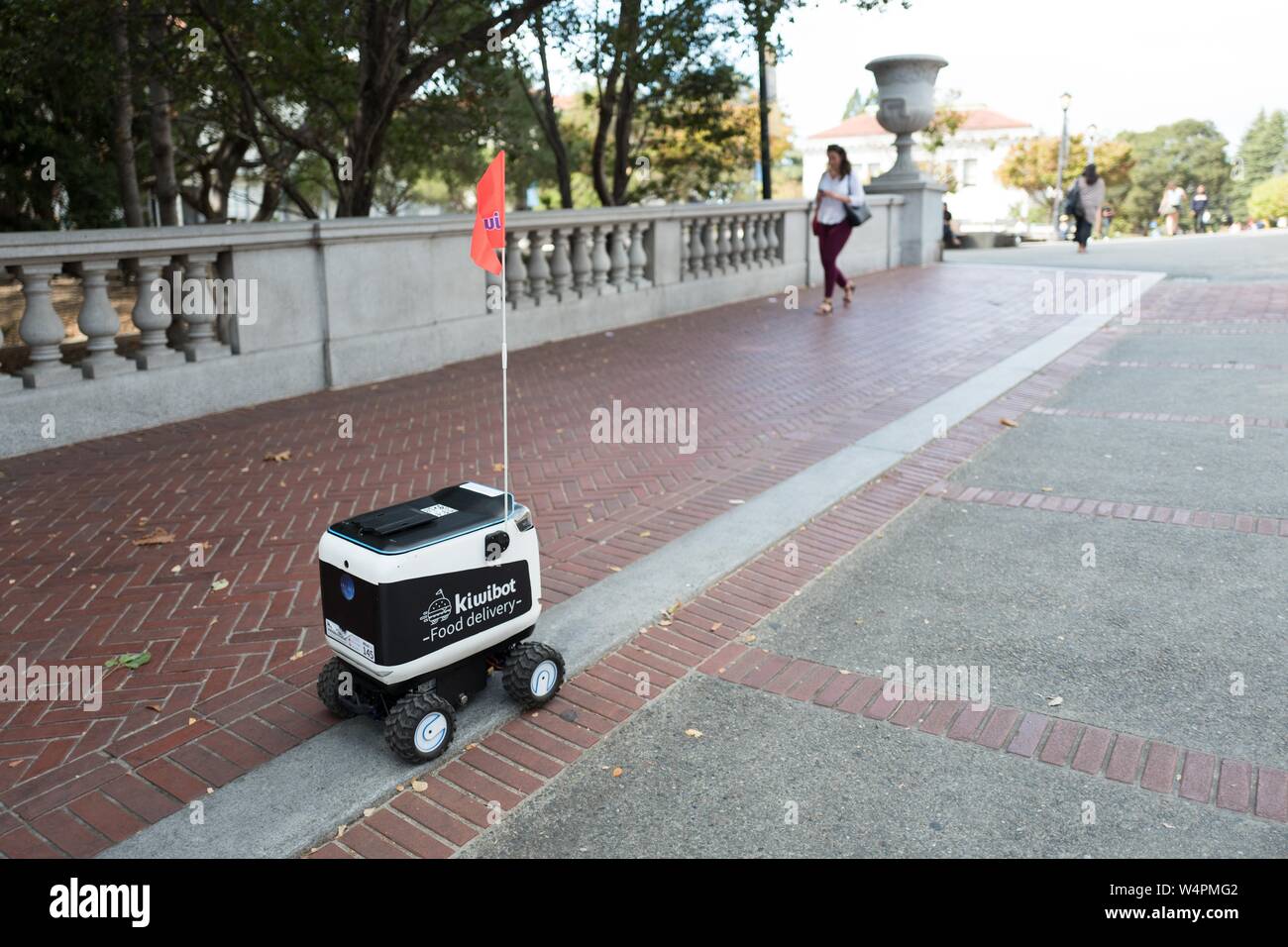 Close-up of Kiwi livraison alimentaire autonome robot le campus de l'université de Berkeley dans le centre-ville de Berkeley, en Californie, avec une étudiante en passant devant, le 9 octobre 2018. () Banque D'Images