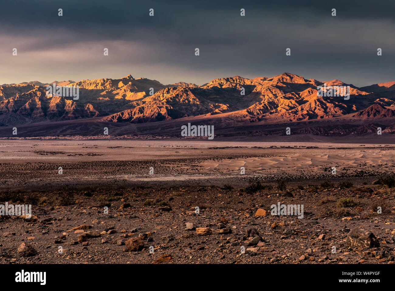 Le coucher du soleil illuminant les montagnes funéraire dans la vallée de la mort avec Mesquite Flat dunes de sable à l'avant-plan. Banque D'Images