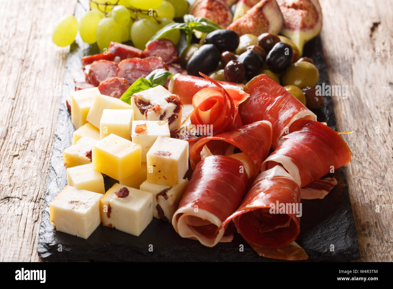 Snack-méditerranéenne de plateau de fromages, jambon prosciutto, raisins, figues, olives et saucisses close-up horizontale. Banque D'Images