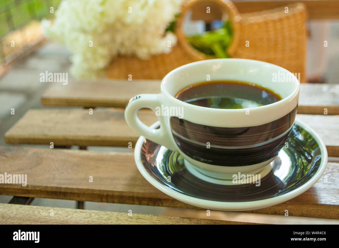 Une tasse de café noir sur une table en bois et un sac de paille avec  hydragea fleurs sur l'arrière-plan Photo Stock - Alamy
