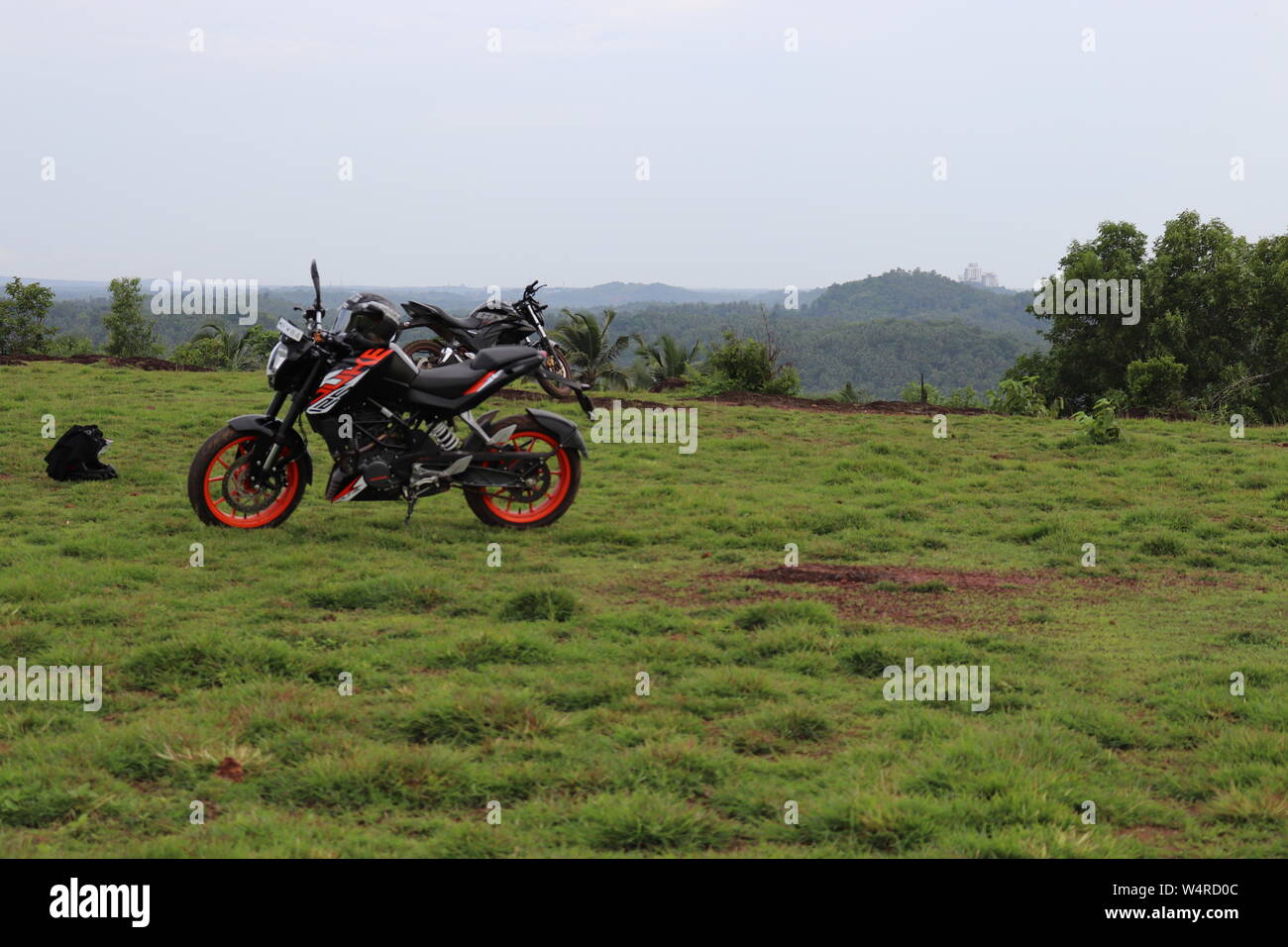 Une orange sports moto reposant sur une colline verte avec de belles montagnes en arrière-plan Banque D'Images