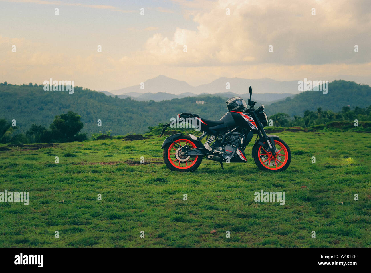 Une orange sports moto reposant sur une colline verte avec de belles montagnes en arrière-plan Banque D'Images