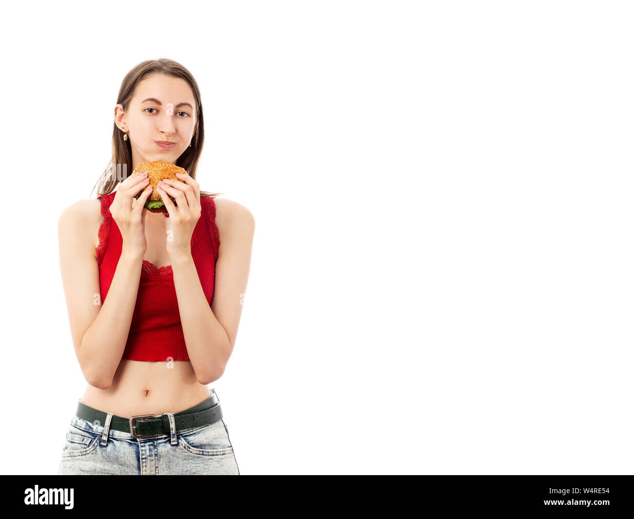 Heureux timide jeune femme mange hamburger sur fond blanc avec copie espace smiling at camera isolée Banque D'Images