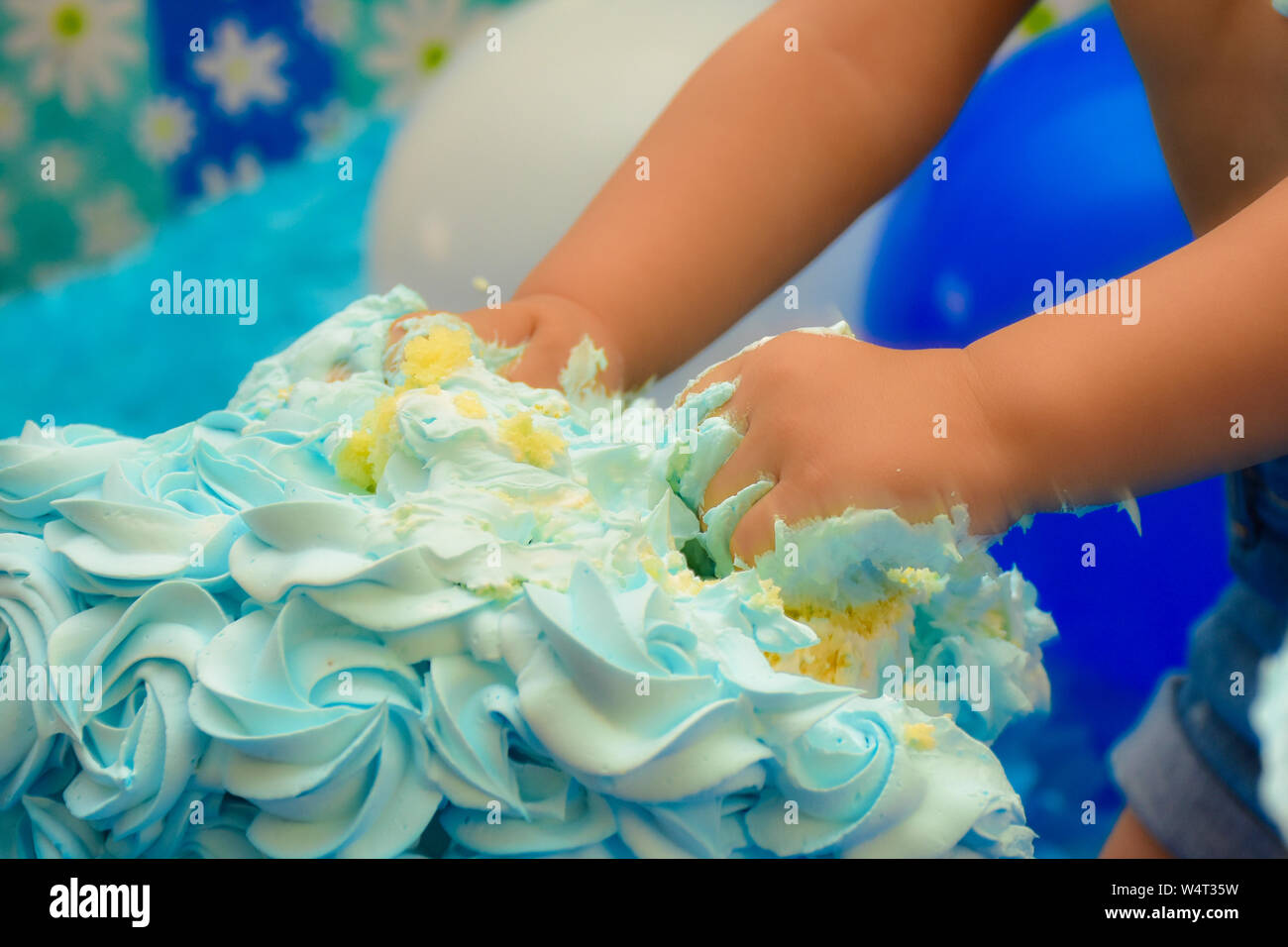 Un gâteau d'anniversaire enfant méconnaissable fracassant avec les mains. Gâteau d'anniversaire smash par petit enfant concept. Banque D'Images