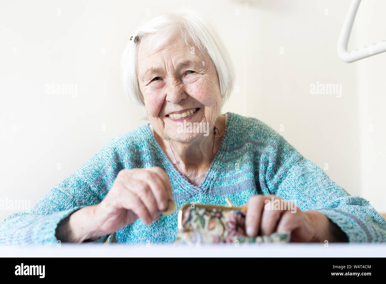 Personnes âgées gaies 96 ans woman sitting at table à la maison heureux avec elle dans son portefeuille d'épargne-retraite après le paiement des factures. Banque D'Images
