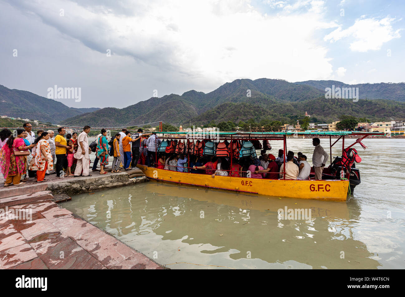 Pèlerins à bord d'un bateau pour traverser le fleuve Ganga dans la ville spirituelle de Rishikesh dans l'état d'Uttarakhand en Inde Banque D'Images