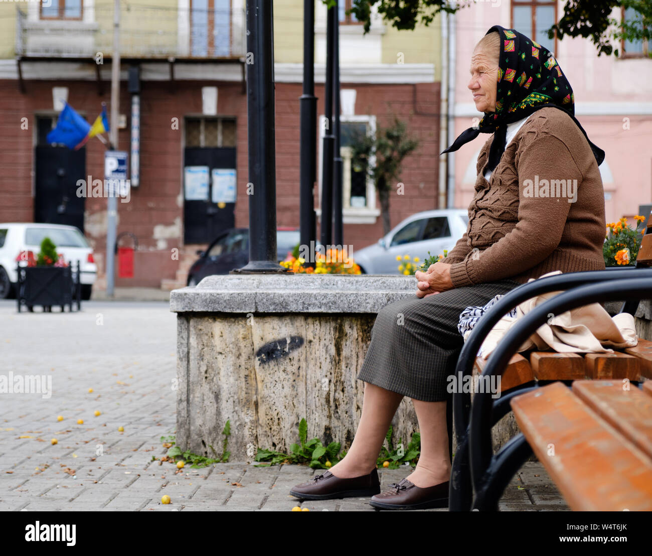 Dame roumaine âgés en jupe, gilet et foulard, assis sur le banc de parc  pendant la messe en priant. Sighet, Roumanie Photo Stock - Alamy