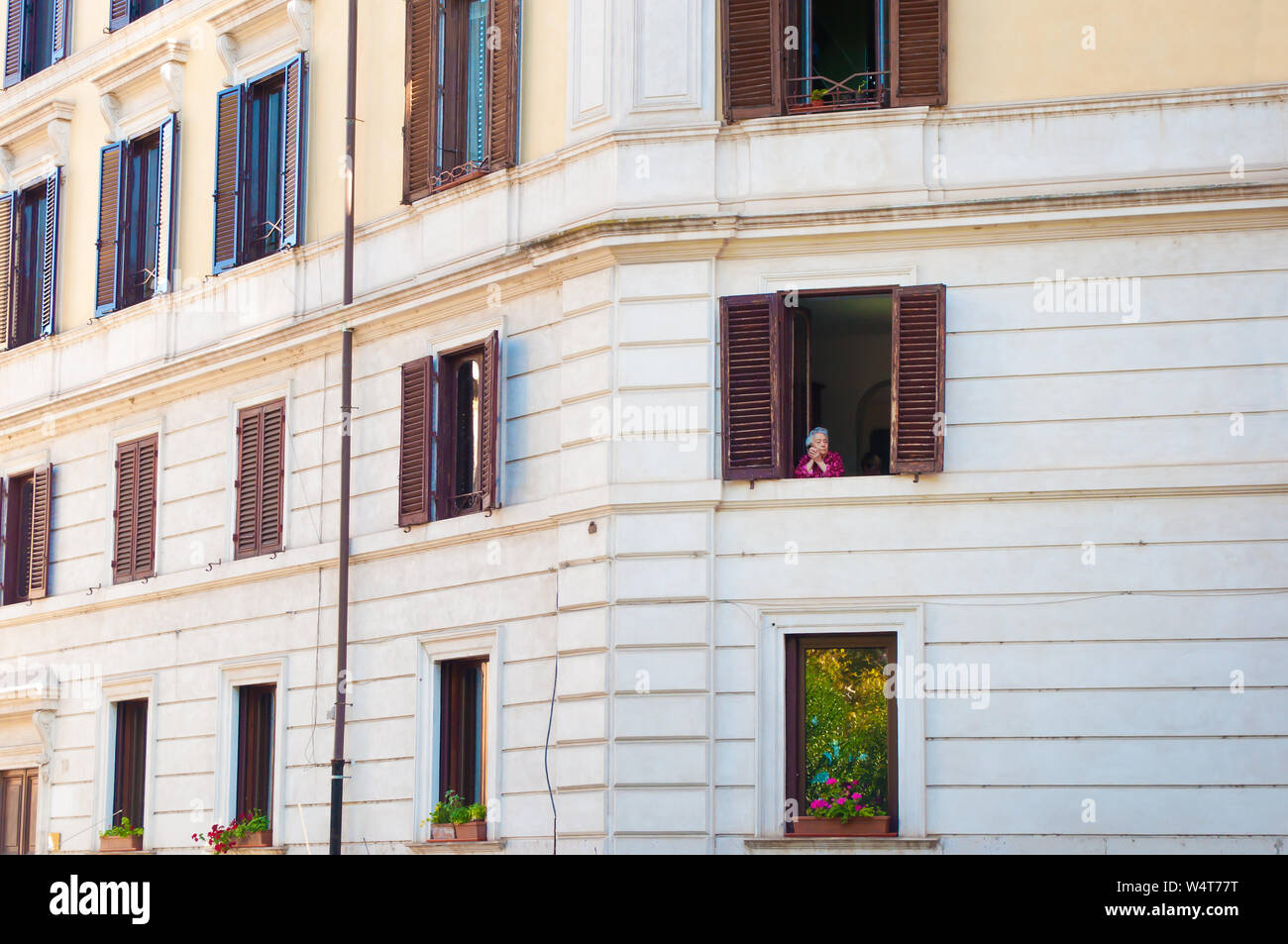Rome, Italie - 28 octobre 2017 : Une vieille dame à la recherche d'une fenêtre avec des volets marron. Conception de la vie, les souvenirs, la joie. - Image Banque D'Images