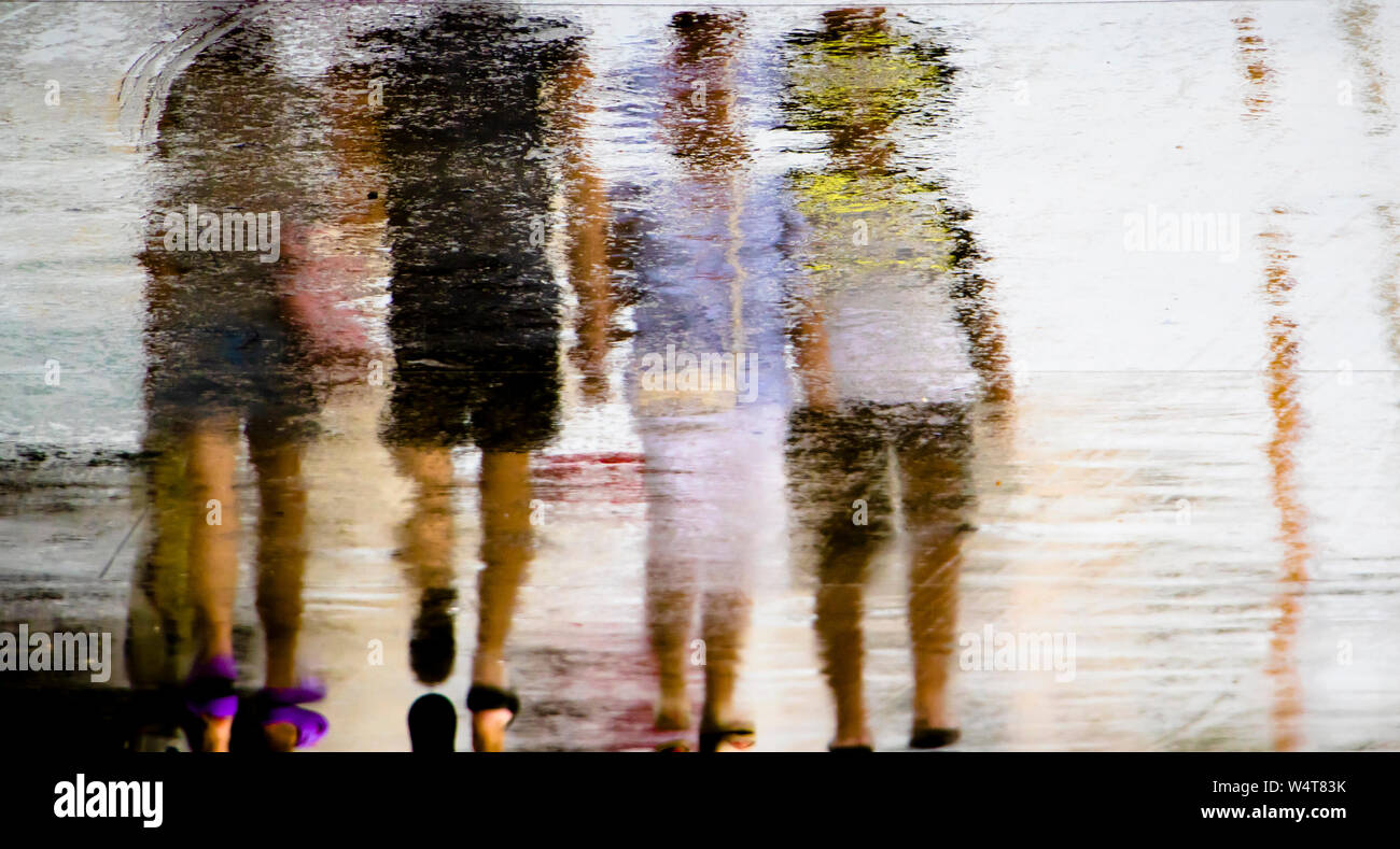 Résumé flou reflet silhouette dans une flaque de personnes marchant sur un jour d'été pluvieux Banque D'Images