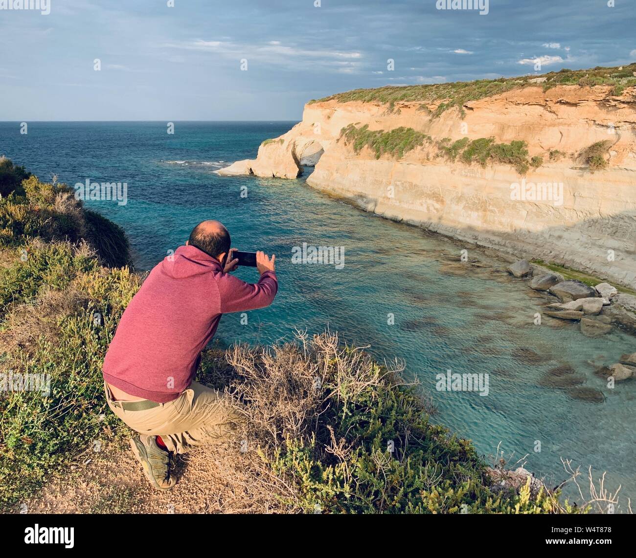 Homme debout par la mer en prenant une photo, Munxarr, Marsaskala, Malte Banque D'Images