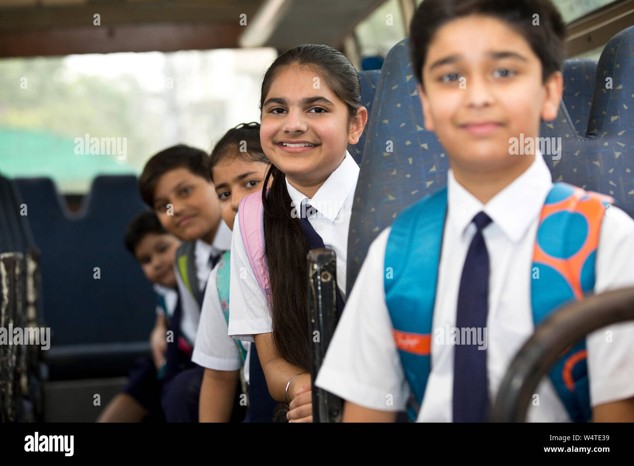 L'école les enfants voyageant en autobus scolaire looking at camera Banque D'Images
