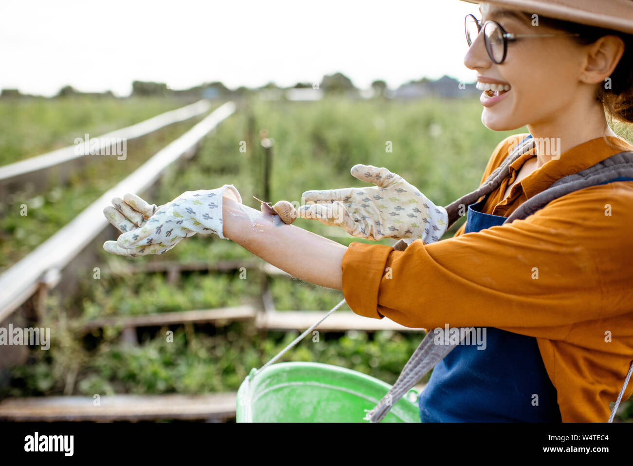 Portrait of a young woman farmer avec escargot sur la main, debout sur les terres agricoles pour la culture des escargots en plein air Banque D'Images