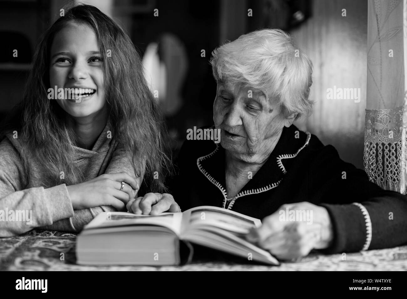 Grandmère, une vieille femme avec sa petitefille une petite fille la lecture d'un livre Grandmère, une vieille femme avec sa petitefille une petite fille la lecture d'un livre