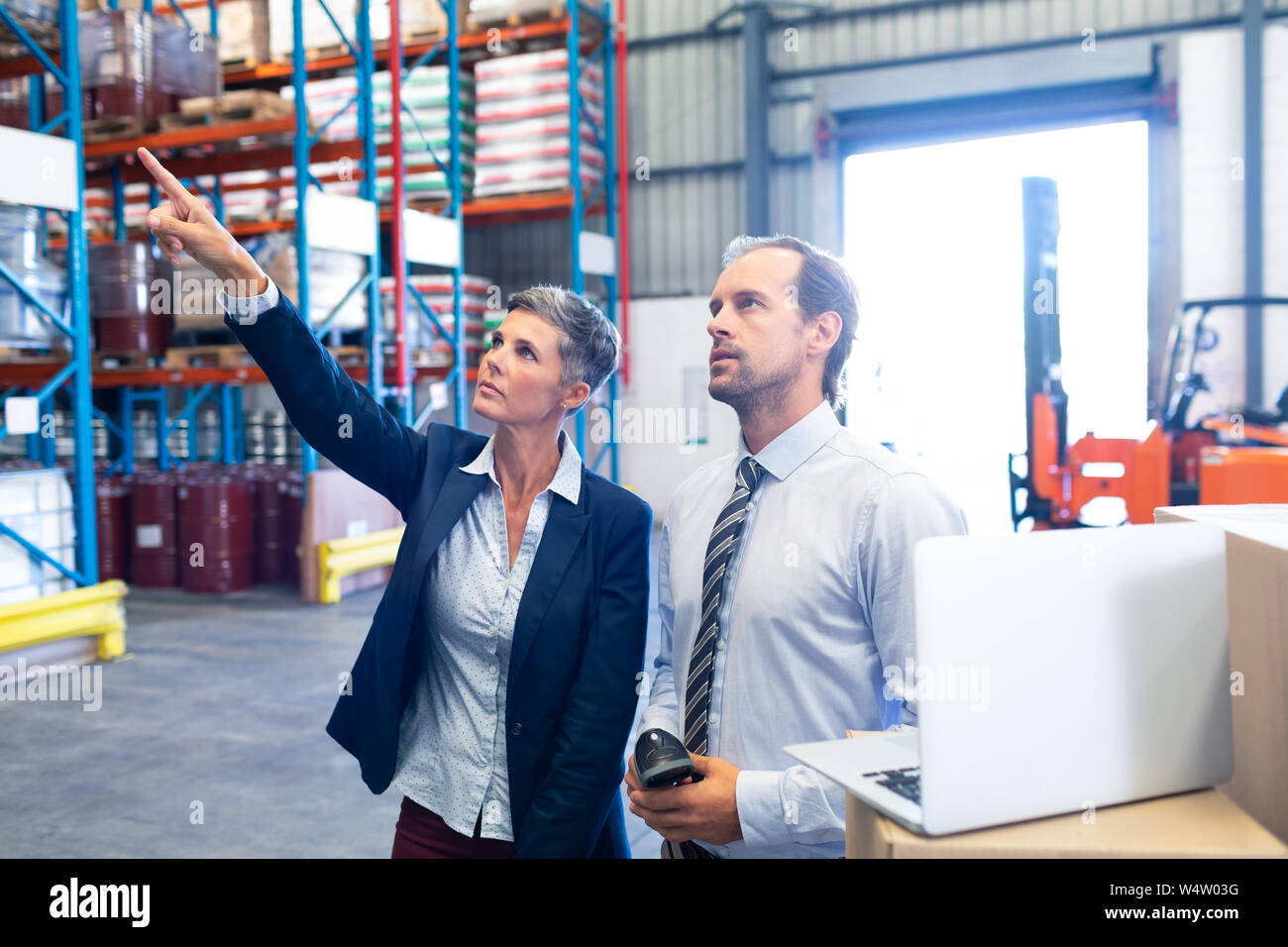Femme debout avec gestionnaire et superviseur de l'entrepôt à distance de pointage Banque D'Images