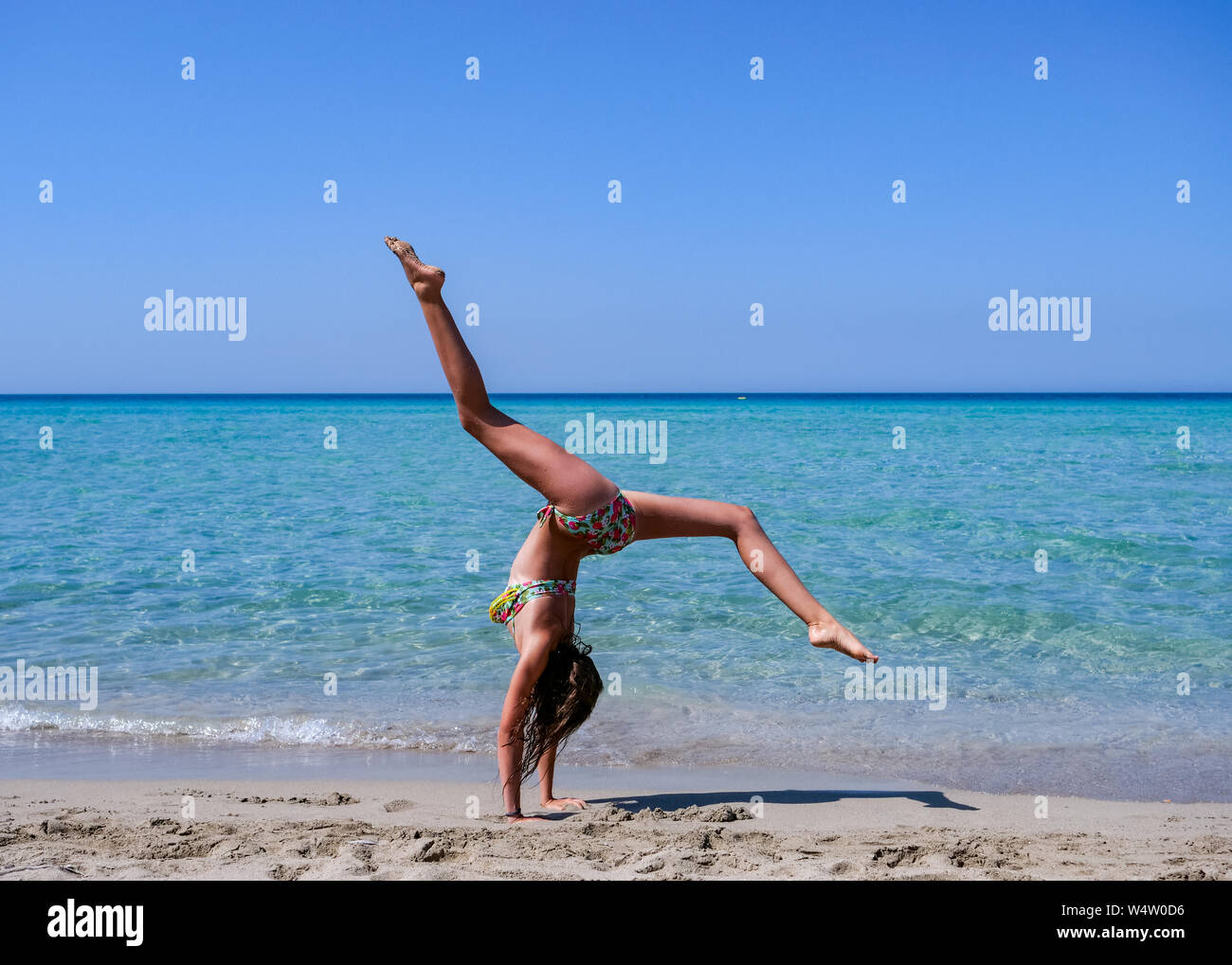 Et Slim athletic girl doing a la gymnastique avant une magnifique plage avec une eau cristalline -locations-fitness-wellness-formation-gymnastique-entraînement Banque D'Images