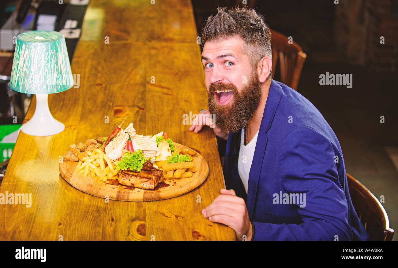 L'homme a reçu de pommes de terre frites repas avec viande et poisson, lavash. Profitez de repas. Il méritent de délicieux repas. Des calories. Vous pourrez vous détendre après une dure journée de travail. Woman costume formel s'asseoir à comptoir bar. Banque D'Images