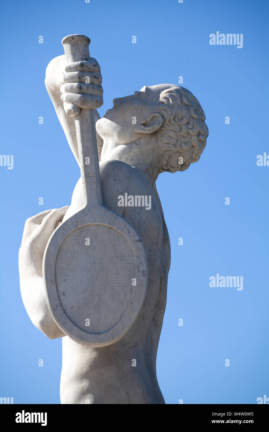 Une statue en pierre d'un joueur de tennis dans le Stadio dei Marmi (en stade) à Rome. La statue a son bras levé pour servir contre un bleu ciel d'été. Banque D'Images