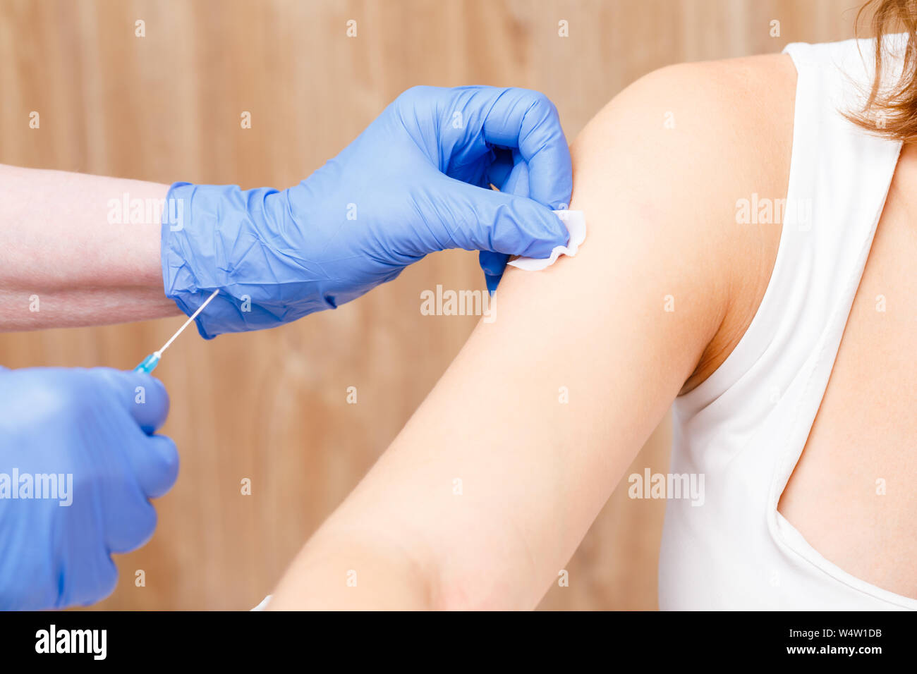 L'assistant médical préparer une injection intramusculaire d'un vaccin contre la désinfection des bras de jeune femme dans une clinique Banque D'Images