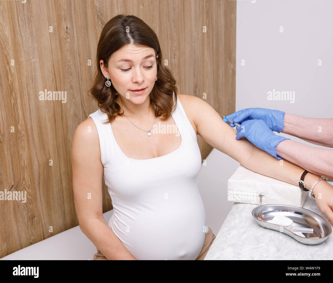 L'assistant médical donnant une injection intramusculaire d'un vaccin sur le bras de femme enceinte dans une clinique - concept de vaccination grossesse Banque D'Images