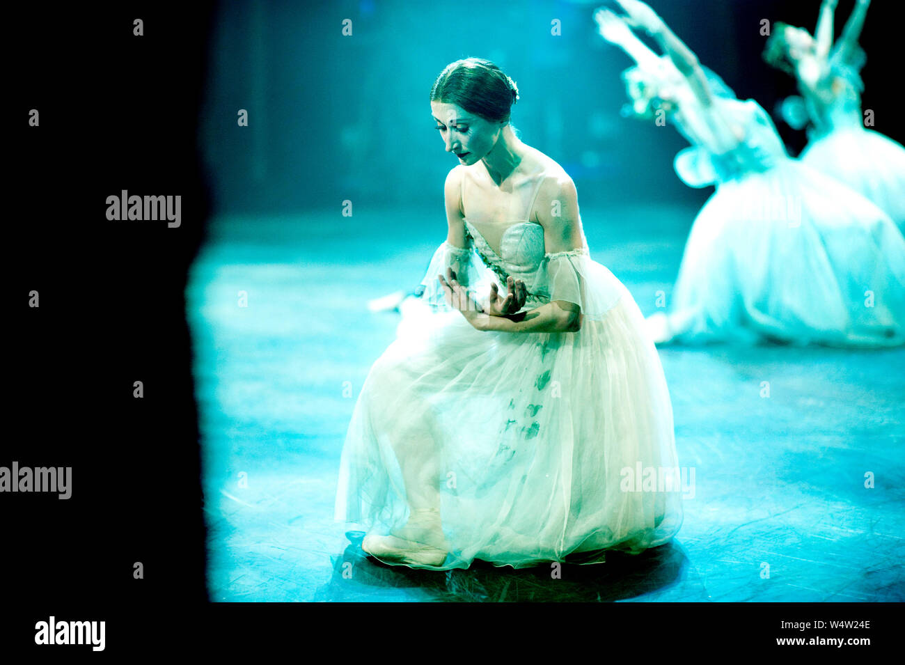 Ballerine Daria Klimentova sur scène en vert-bleu de l'éclairage. Elle est dans une révérence dans un ballet de Giselle Banque D'Images